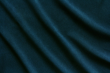 Fototapeta na wymiar dark green dense fabric with large diagonal folds, abstract background