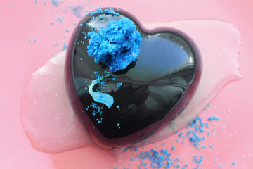 Heart shaped dessert with blue petal and decorations on orange pink background