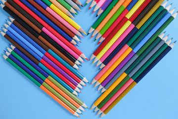 School concept. Closeup images of many color pencils on blue background. Flat lay, top view, copy space.