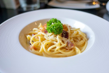 Pasta carbonara or spaghetti with ham, parsley, bacon, parmesan cheese in white dish.