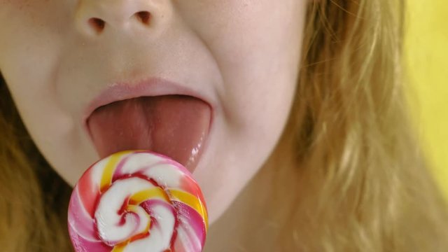 Little girl with a lollipop on a Yellow background. Close up portrait