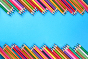 School concept. Creative composition of many color pencils on blue background. Flat lay, top view, copy space.