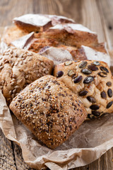 Gold rustic crusty loaves of bread and buns on wooden background. Still life captured from above top view, flat lay.