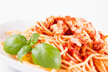 Spaghetti bolognese with melted parmesan cheese decorated with basil on a white background	