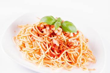 Spaghetti bolognese with melted parmesan cheese decorated with basil on a white background	