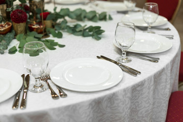 The wedding table setting is decorated with fresh flowers in a brass bowl and golden candles in brass candlesticks. Wedding floristry. Banquet table for guests. Bouquet with dahlias and eucalyptus