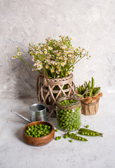 Beautiful summer still life with green peas and wildflowers on a light background.