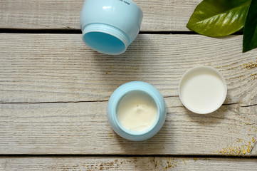 face cream on white wooden table background. Cosmetic cream container on white wooden background with flowers. Face cream banner.