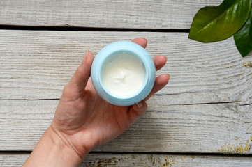Face cream on vintage wooden white background with female hands. Anti-aging cream in the hands. Female hands holding a jar of cream. Body cream