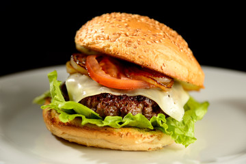 Hamburger on white plate with black background