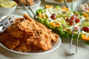 Fried pork and chicken cutlets in a wedding banquet with cheese and salad in the background