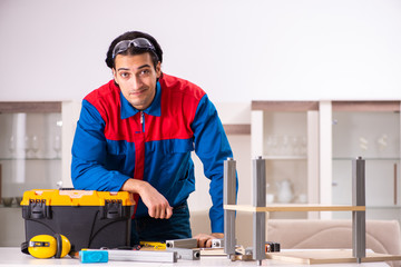 Young contractor repairing furniture at home 
