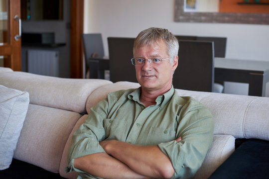 Middle-aged handsome man at home front of the camera on the sofa