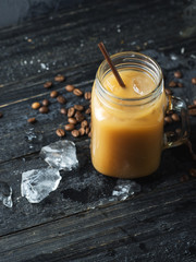 Glass jar of cold coffee with a straw on a dark table