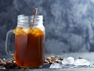 Glass jar of iced coffee on a dark wooden table close-up