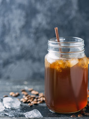 Glass jar of iced coffee on a dark wooden table close-up