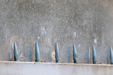 Metallspitzen auf einem Metalltor oder Eisentor vor einer alten Steinwand zeigen...