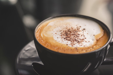 close up modern hot black coffee the cappuccino on dark background with coffee bubble foam pattern and texture in black cup looking and feel so delicious on glasses table in coffee shop.