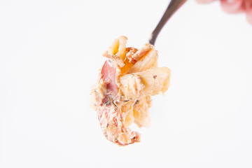 Pasta - penne with white cream sauce with bacon and jalapeño peppers on a fork	