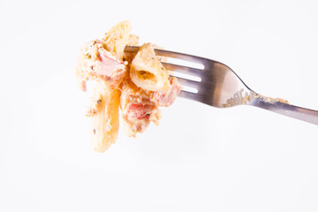 Pasta - penne with white cream sauce with bacon and jalapeño peppers on a fork	
