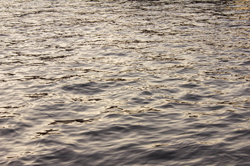 The shimmering texture of the dark blue sea and ocean with highlights from the evening sunset on the water. Natural background on the sea surface.