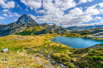 View at Midi Ossau mountain peak and Lake Roumassot, in Ayous-Bious valley in French Atlantic Pyrenees, as seen in October. Aquitaine, France. - obrazy, fototapety, plakaty