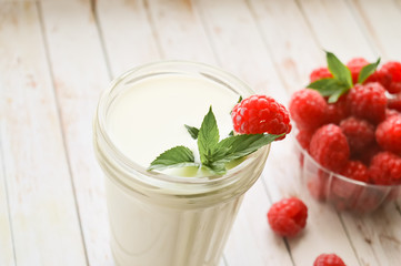 A glass of milk and fresh raspberries with mint on a white background, close-up. Healthy, proper nutrition. Diet.