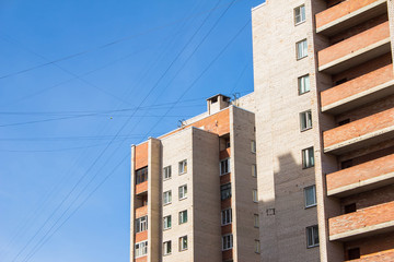 Multi-storey residential buildings in an overpopulated residential dormitory area against a blue sky and intersecting black wires and communications. Dense building in Petersburg. Soviet architecture.