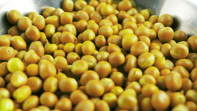 Yellow pease rotating on dark texyure surface. Close up 4k footage.