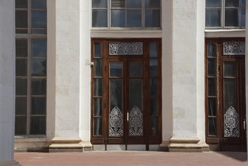 one brown old door of wood and glass on a gray concrete wall with columns