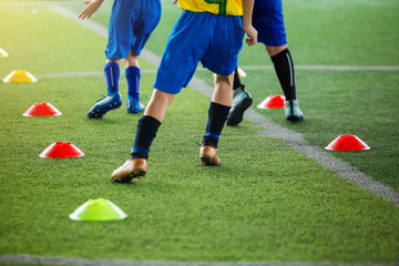 kid soccer players Jogging and jump between cone markers on green artificial turf for soccer...