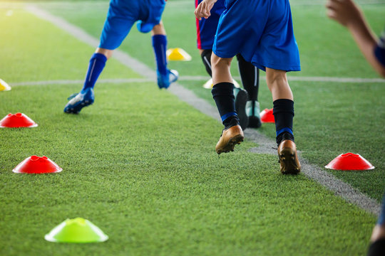 kid soccer players Jogging and jump between cone markers on green artificial turf for soccer training.