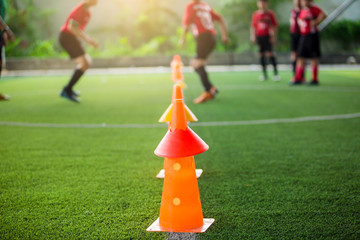 orange marker cones on green artificial turf for soccer training. Soccer equipment with blurry...