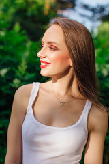 Young woman dressed in white shirt in summer park