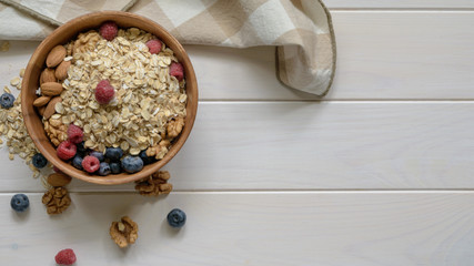 oatmeal with blueberries, raspberries, almond and walnuts in a wooden bowl on a black wooden table