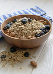 oatmeal with blueberries, almond and walnuts in a wooden bowl on a black wooden table
