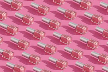 transparent glass bottles of nail polish on pink background