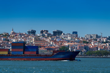 A container ship entering the port with the city of Lisbon skyline on the background; Concept for...