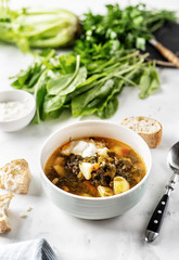 Sorrel soup with sour cream in white bowl