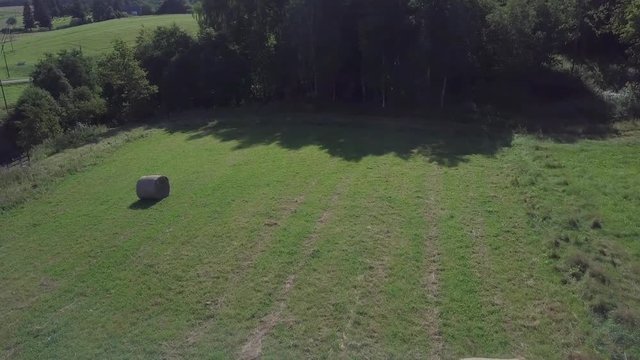 Aerial smooth drone shot of meadow with a hay rolls in Lithuanian rural countryside of Samogitia region.