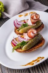 Halves baked potato with pickled cucumber, dill, salo and onion on wooden table