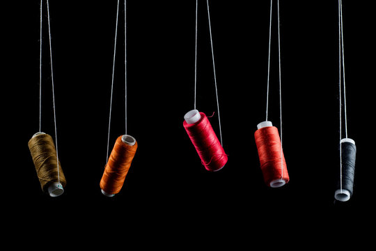 Black, bronze, orange, red and pink threads on babin soaring suspended on white thread on a black background, isolate