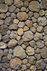Texture of an old stone wall from uneven different ancient stones of various forms