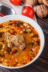 Georgian soup. Kharcho with rice, tomato, beef, garlic and herbs in bowl on wooden table