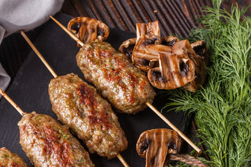 Shish kebab on the skewers with grilled mushrooms on rustic table