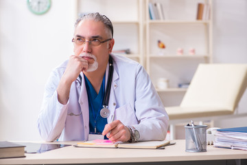 Obraz premium Old male doctor working in the clinic 
