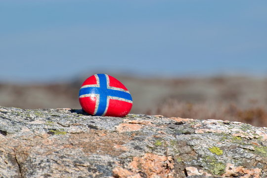 Image of the flag of Norway on a stone, between sea pebbles and seashells. Concept of Norwegian Constitution Day.  Celebrated on May 17.