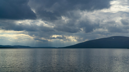 Sunlight through the clouds over the rocky northern lake