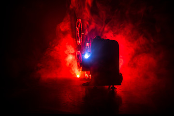 Old vintage movie projector on a dark background with fog and light. Concept of film-making.