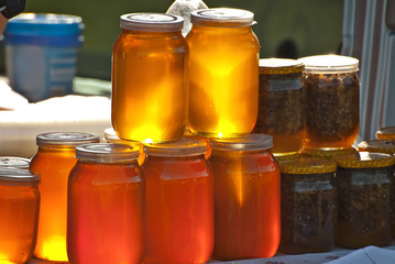 Different types of honey on the table. The colorful jars of honey are sold at the agricultural produce fair.